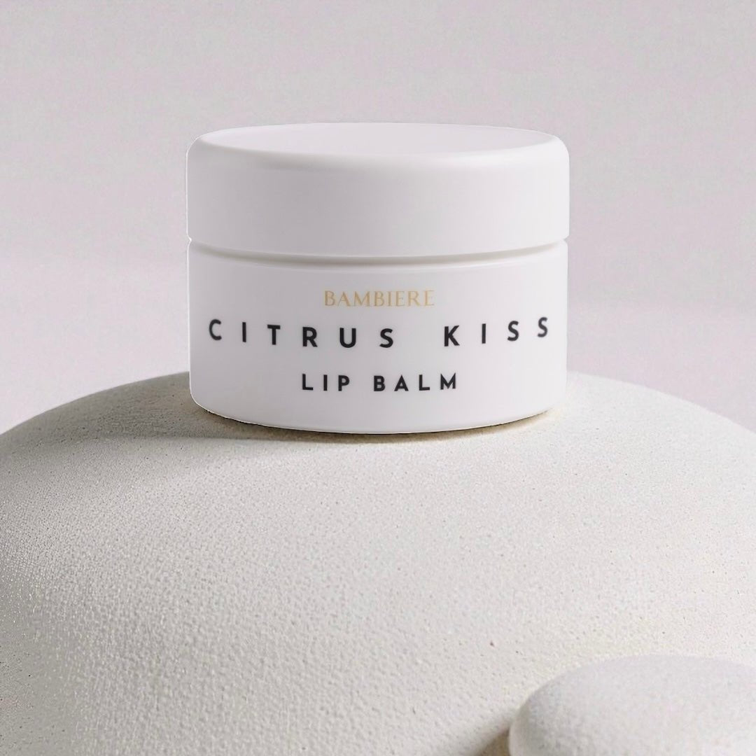 White lip balm container labeled 'Citrus Kiss' on a textured white surface with a light gray background.